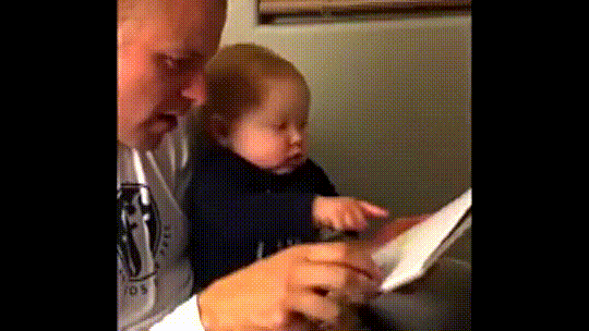 An adorable baby mimics his dad in surprise as they read together